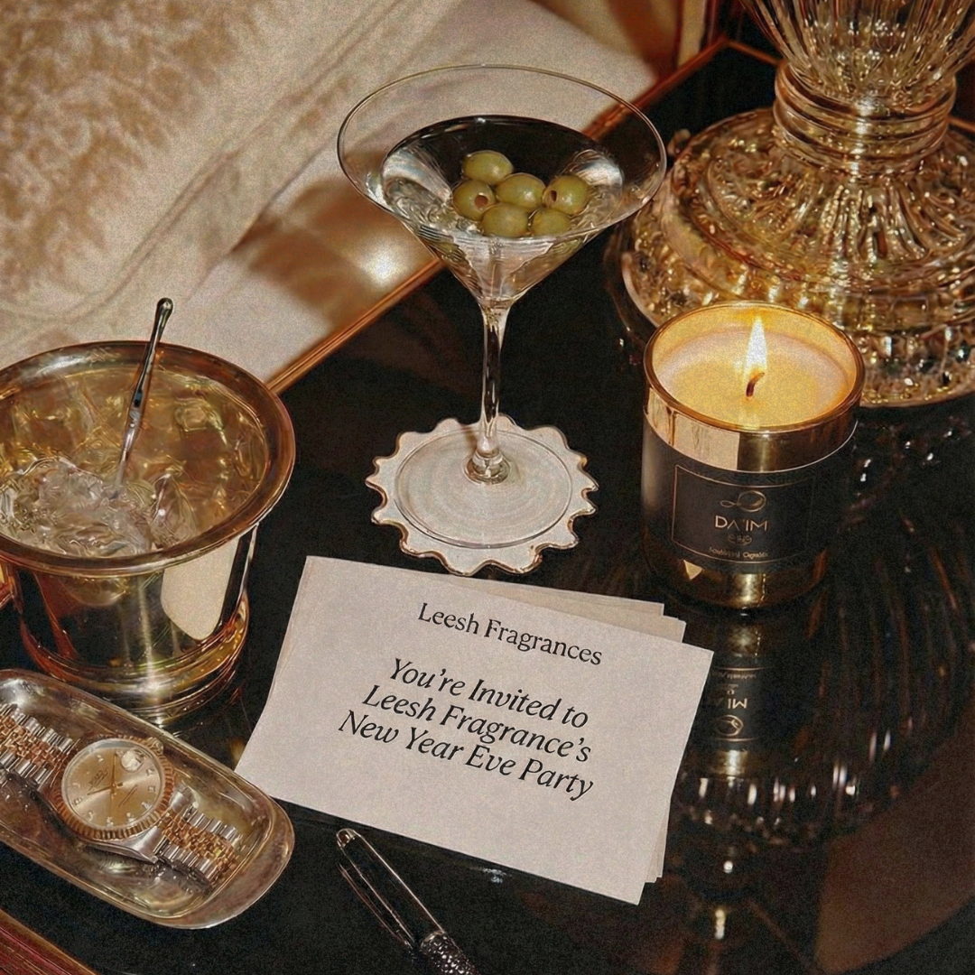 Festive table setting with a cocktail, candle, and invitation to a New Year's Eve party. Da'im oud candle by leesh fragrances at New Year 2026 celebration, styled in a cinematic, editorial setting with warm light, shadows and luxury ambience
