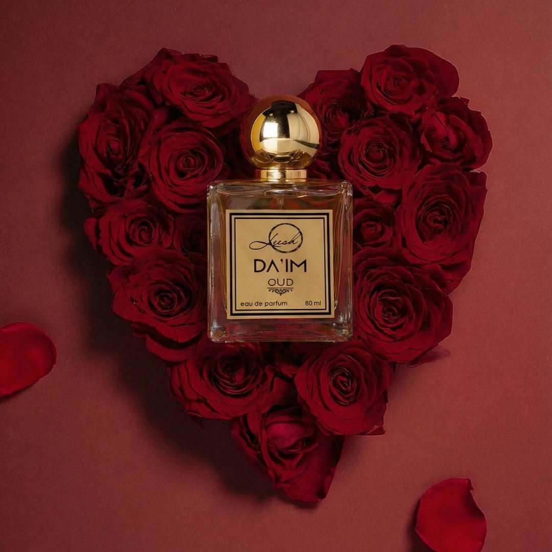 Perfume bottle with gold cap on a heart-shaped arrangement of red roses against a red background Da’im Oud by Leesh Fragrances displayed on a heart-shaped bed of red roses for Valentine’s Day
