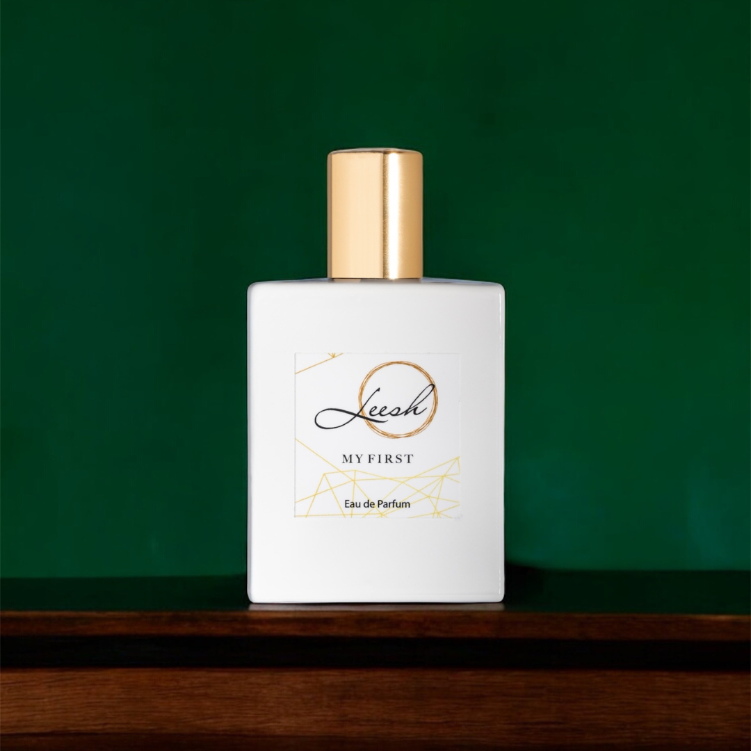 Her My First by Leesh — a flirty and empowering fragrance for women. Featuring patchouli, cedarwood, vanilla, jasmine, rose, ylang-ylang, amber, and musk. Elegant bottle shot with warm amber lighting, reflecting confidence and unforgettable moments.
