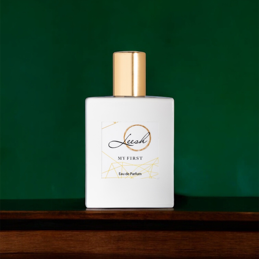 Her My First by Leesh — a flirty and empowering fragrance for women. Featuring patchouli, cedarwood, vanilla, jasmine, rose, ylang-ylang, amber, and musk. Elegant bottle shot with warm amber lighting, reflecting confidence and unforgettable moments.
